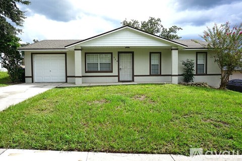 A house with a brown roof and white walls with a small front yard.