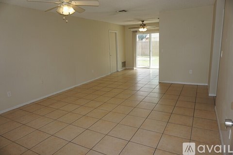 A spacious room with tile flooring and a ceiling fan.
