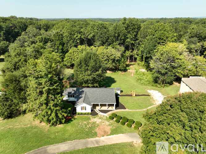 A house surrounded by trees in a lush green landscape.