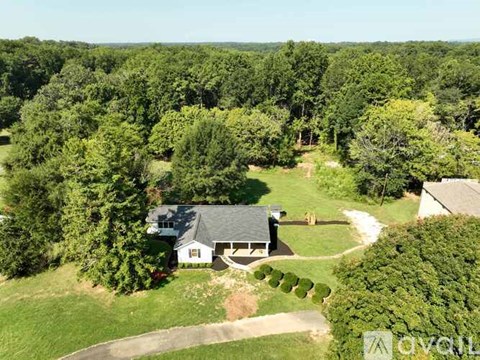 A house surrounded by trees in a lush green landscape.