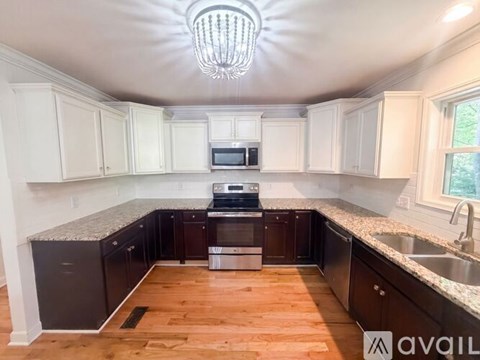 A kitchen with white cabinets and a wooden floor.