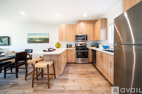 A kitchen with wooden cabinets and a stainless steel refrigerator.