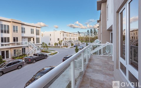 A balcony overlooks a street with cars and buildings.