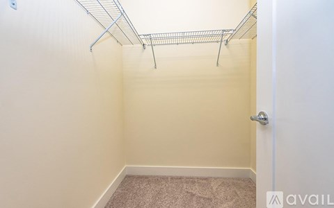 A small, empty room with a wire shelf above a carpeted floor.