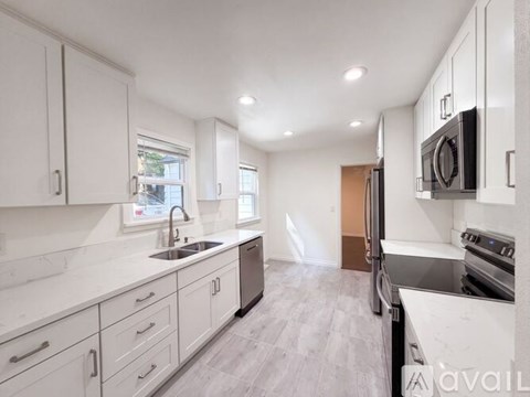A kitchen with white cabinets and a black stove top oven.