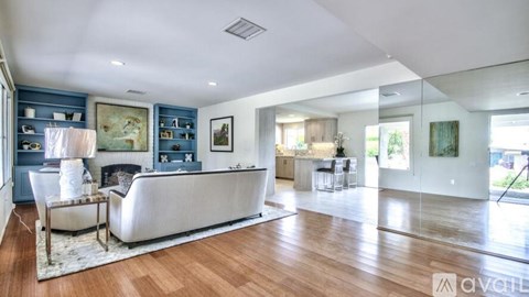A spacious living room with a white sofa and wooden flooring.