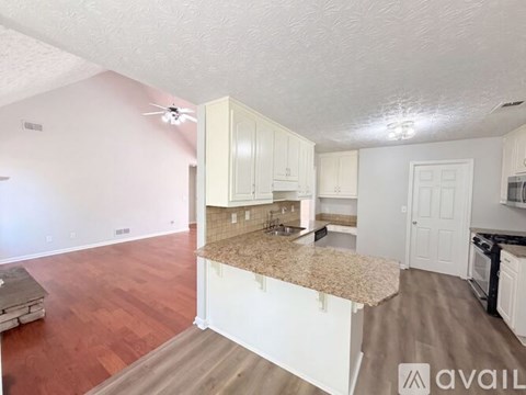 A kitchen with white cabinets and a granite countertop.