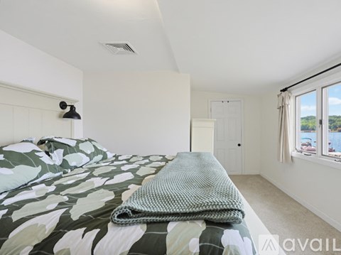 A bedroom with a bed covered in a leaf patterned comforter.