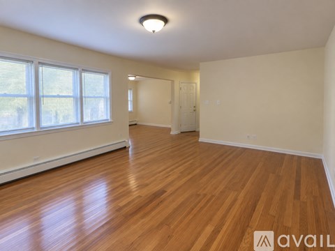 A spacious room with wooden flooring and a large window.