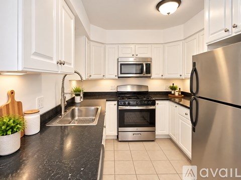 A kitchen with white cabinets and a black countertop.