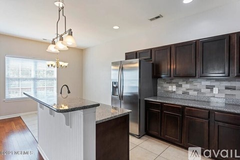 A kitchen with dark brown cabinets and a granite countertop.