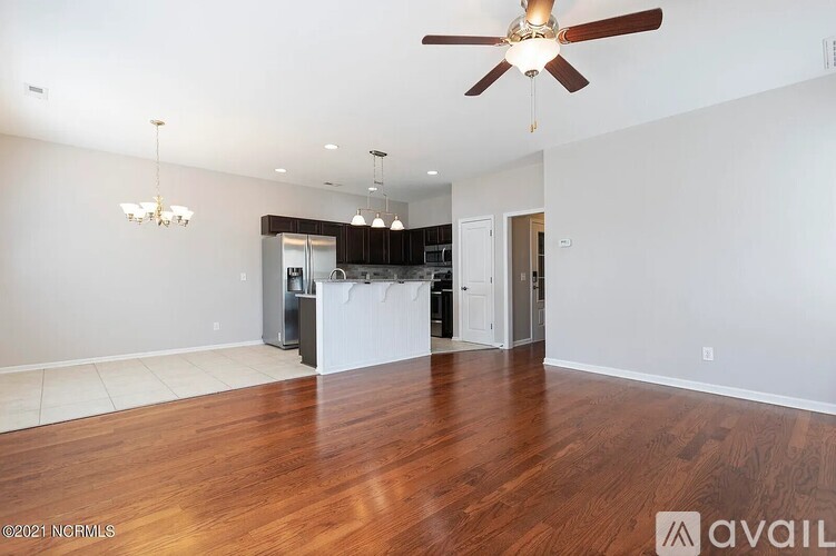A spacious living room with a ceiling fan and hardwood floors.