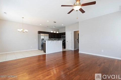 A spacious living room with a ceiling fan and hardwood floors.