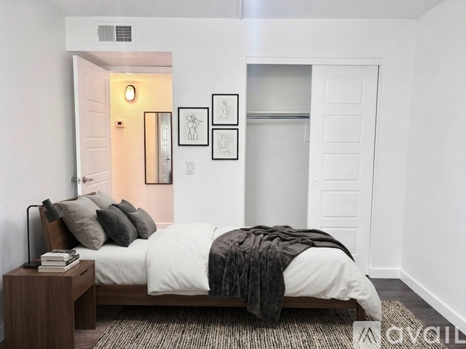 A bedroom with a bed, nightstand, and artwork on the wall.