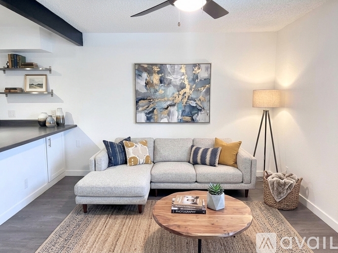 A living room with a grey couch, a coffee table, and a painting on the wall.