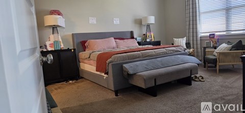 A bedroom with a large bed and a nightstand with a lamp.