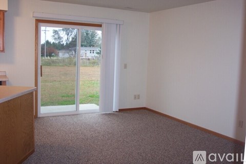 A room with a carpeted floor and a sliding glass door leading to a grassy area.