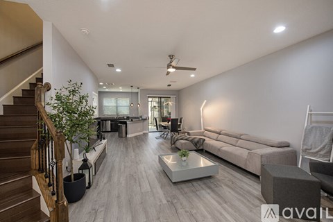 A spacious living room with a staircase on the left and a couch on the right.