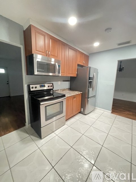 A kitchen with a stove top oven, microwave, refrigerator, and cabinets.