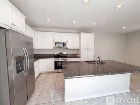A kitchen with white cabinets and a granite countertop.