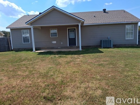A house with a grey siding and a dark grey door is surrounded by a grassy area.