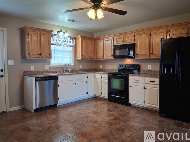A kitchen with black appliances and wooden cabinets.