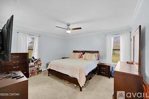 A bedroom with a bed, dresser, and tv.