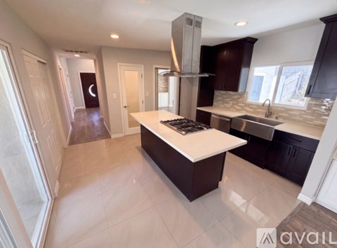 A modern kitchen with dark wood cabinets and a white island.