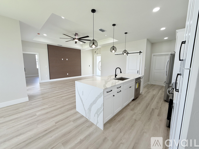 A modern kitchen with white cabinets and a wooden floor.