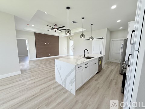 A modern kitchen with white cabinets and a wooden floor.