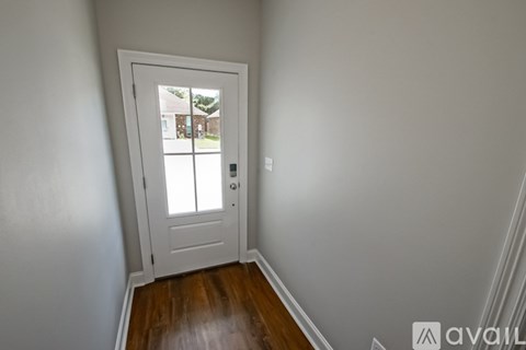 A white door with a glass window is in a room with wooden floors.