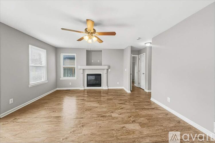 A spacious living room with a ceiling fan and hardwood flooring.