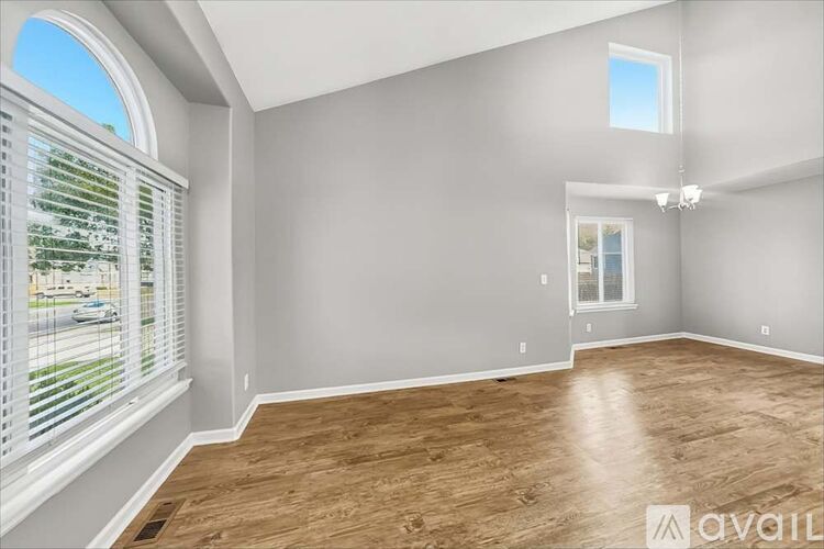A room with wooden flooring and a window with blinds.