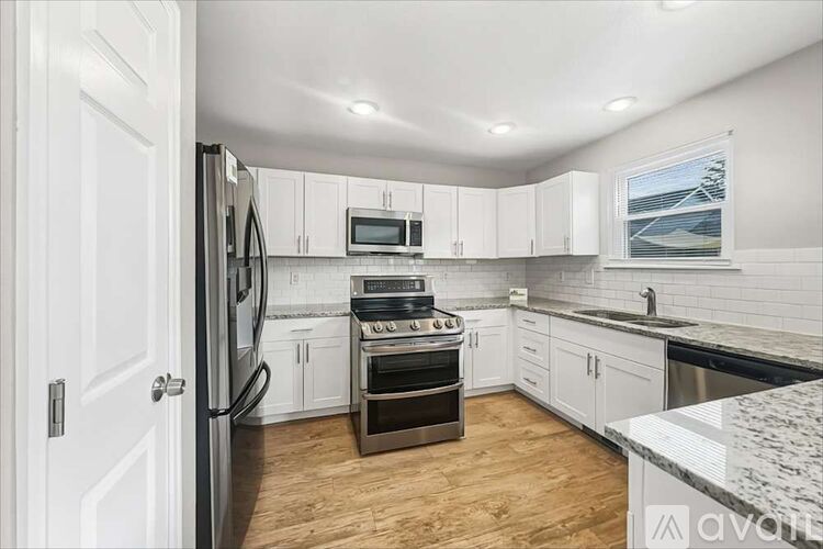 A kitchen with white cabinets and a black countertop.