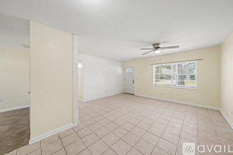 A spacious room with a ceiling fan and a window with a view of the outside.