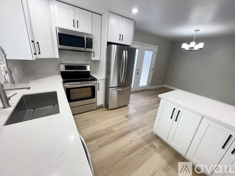 A kitchen with white cabinets and a stainless steel refrigerator.
