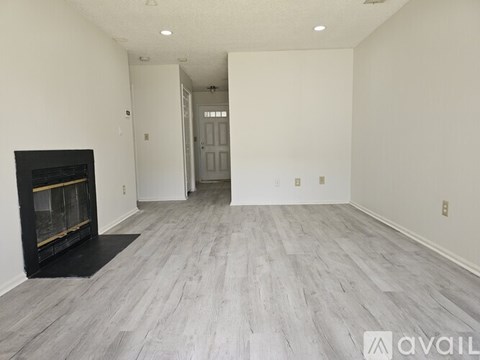 A spacious room with a fireplace and a doorway leading to another room.