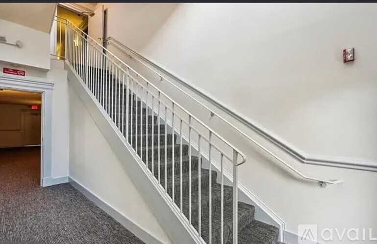 A staircase with a metal railing and a red sign above it.