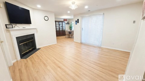 A living room with a fireplace and a television mounted above it.