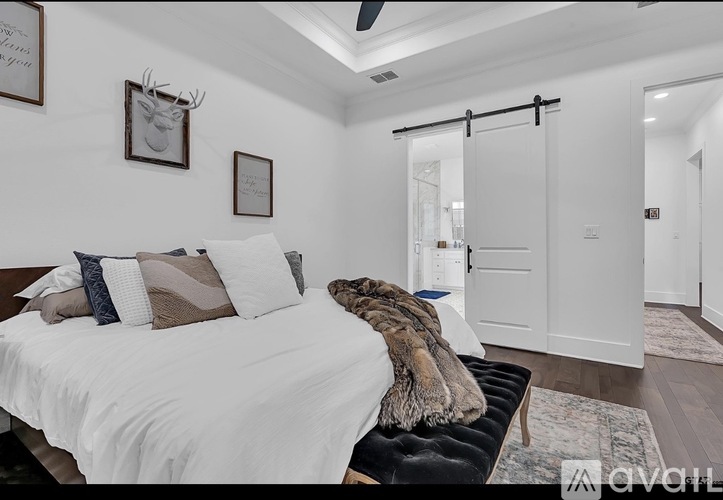 A bedroom with a white bed and a black bench.