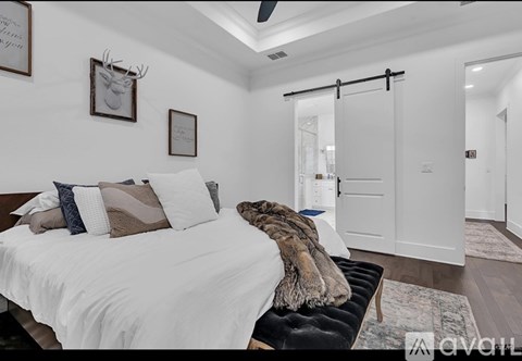 A bedroom with a white bed and a black bench.