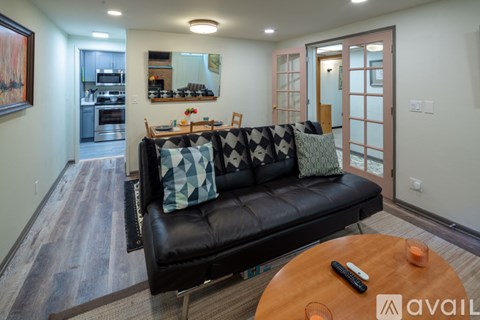 A living room with a black couch and a wooden coffee table.