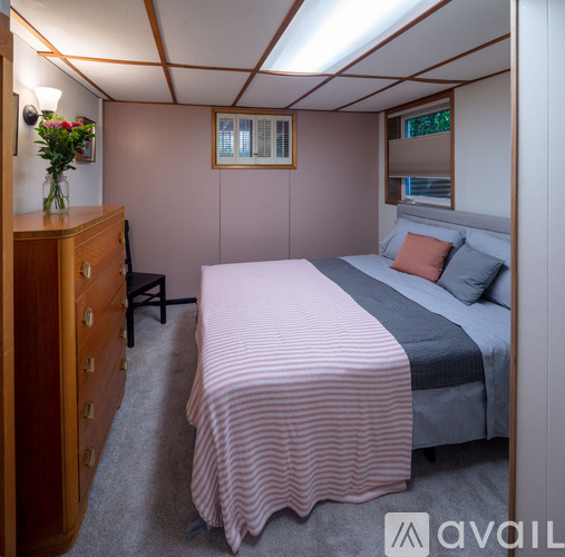 A bedroom with a bed, nightstand, and a dresser with a vase of flowers on top.