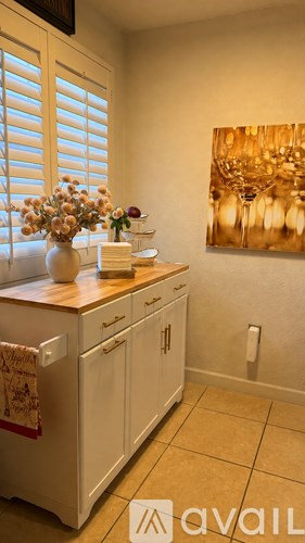 A kitchen with white cabinets and a painting on the wall.