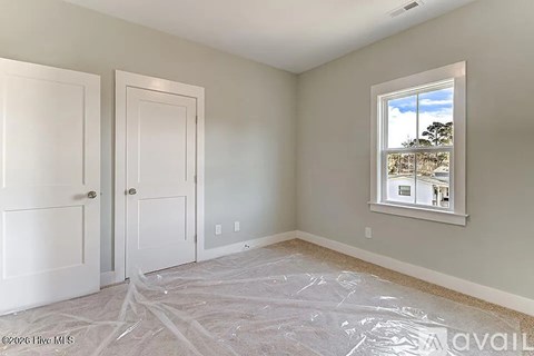 A room with white doors and a window showing a view of trees and houses.