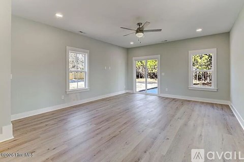 A spacious room with wooden flooring and a ceiling fan.