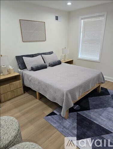 A bedroom with a bed, nightstand, and a painting on the wall.