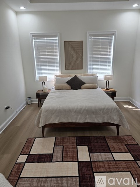 A bedroom with a large bed and a rug on the floor.