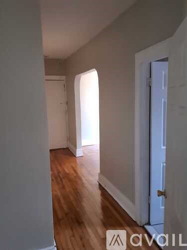 A hallway with wooden floors and white walls.