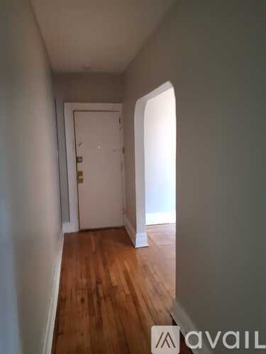 A hallway with a door and a wooden floor.